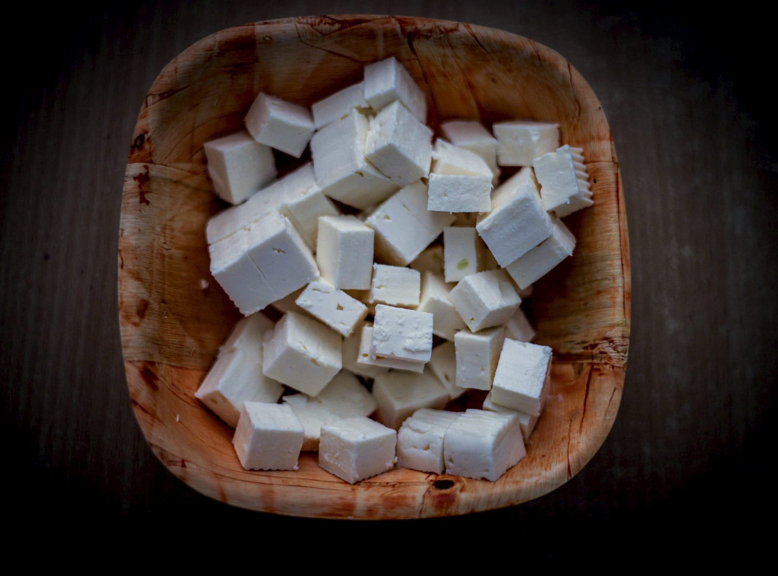 Cubes of fresh paneer in a carved wooden bowl
